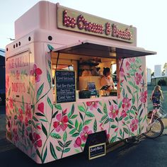 a pink food truck with flowers painted on it