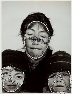 two women with their faces covered in wire and words written on her face, both looking at the camera