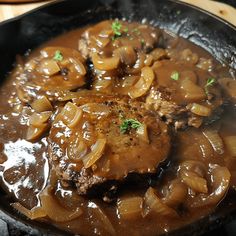 a skillet filled with meat and onions on top of a table