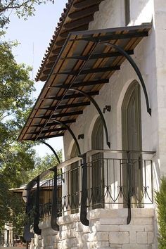 an outside view of a white building with wrought iron railings and arched glass windows