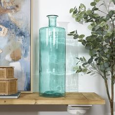 a blue vase sitting on top of a wooden shelf next to a potted plant