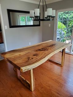 a wooden table sitting on top of a hard wood floor next to a window in a living room