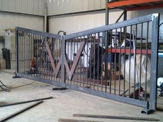 a large metal gate with two horses behind it in a warehouse or workshop, surrounded by tools and equipment