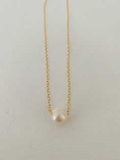 Just A Pearl! This simple yet elegant necklace is part of my Just A Pearl collection. One single pearl dangles from a delicate gold necklace. It measures 16 inches and length and can be adjusted to 15 inches for choker length. Classic Pearl White Necklace With Delicate Chain, Classic Pearl Necklace With Delicate Chain, Minimalist Pearl Charm Chain Necklace, Minimalist Pearl Chain Necklace With Pearl Charm, Classic Gold Charm Necklace With Pearl Drop, Classic Gold Charm Necklace With Pearl Chain, Classic Gold Pearl Chain Charm Necklaces, Classic Pearl Charm Necklace With Pearl Pendant, Classic White Charm Necklace With Pearl Drop