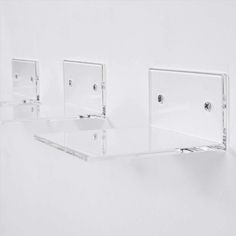 three clear glass shelves are hanging on the wall