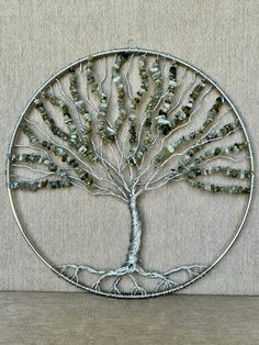 a metal wire tree with green beads on it's branches and roots in the shape of a circle