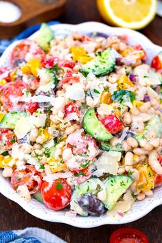 a salad with cucumbers, tomatoes, and other veggies in a white bowl