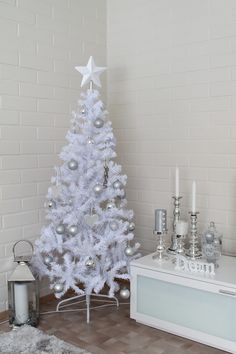 a white christmas tree with silver ornaments and candles