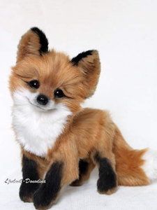 a small stuffed fox sitting on top of a white surface