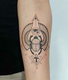 a black and white tattoo with an egyptian scarp on the arm, in front of a