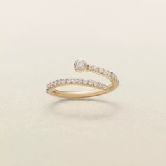 a yellow gold ring with diamonds on the top and bottom, sitting on a white surface