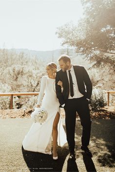 a bride and groom walking together in the sun