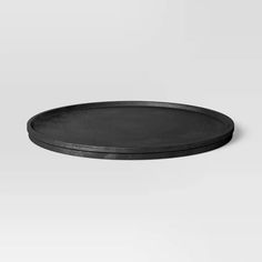 an empty black plate sitting on top of a white surface with no one around it