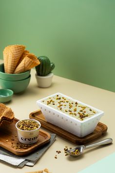 a table topped with bowls filled with food next to crackers and spoons on top of wooden cutting boards