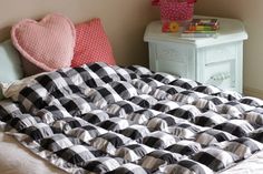 an unmade bed with black and white checkered comforter on top of it