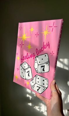 a hand holding up a pink greeting card with dices on it