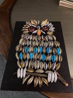 an owl brooch is sitting on top of a black piece of wood with blue and white beads