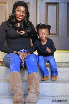 a woman sitting on the steps with her son, who is wearing blue jeans and brown boots