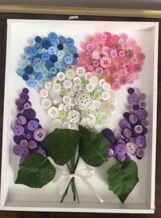 a white box filled with lots of different colored buttons next to a leaf and flower