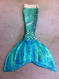 a blue and green mermaid tail laying on the ground