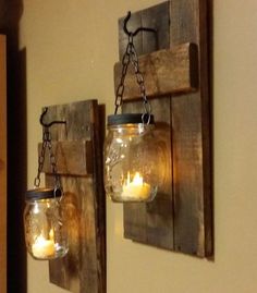 two mason jars are hanging on the wall with candles in them as if they were made from wood planks