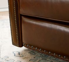 a brown leather couch sitting on top of a rug