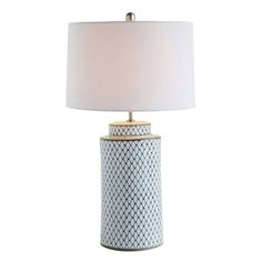 a table lamp with a white shade on top and a gold trim around the base