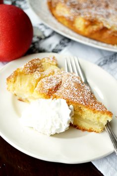 a piece of pie on a plate with whipped cream and an apple in the background