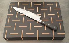 a knife is sitting on top of a black and brown box with gold lines around it