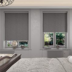 a bedroom with gray walls and white bedding, two windows covered in shades that look out onto the trees