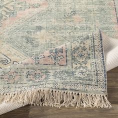 a rug with fringes on top of it and a wooden floor in the background