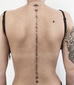 the back of a woman's body with tattoos on her upper and lower back