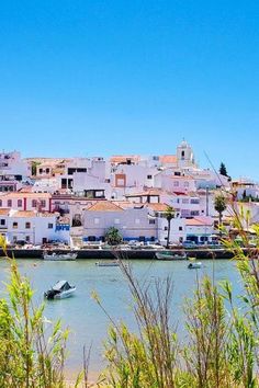 boats are in the water next to some buildings and grass on the shore with blue sky