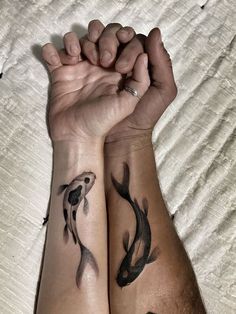 two people holding hands with tattoos on their arms, both showing the same tattoo design