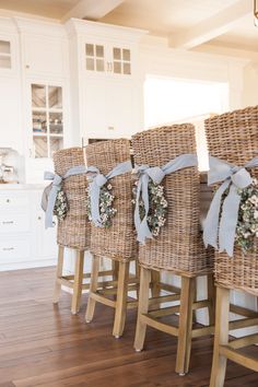 a row of wicker chairs with bows tied around them in front of a kitchen island