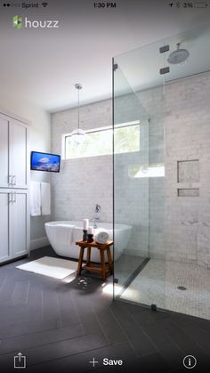 a large bathroom with a walk in shower next to a white tub and sink under a flat screen tv