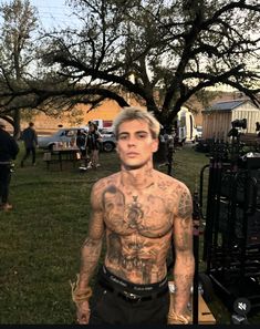 a man with tattoos standing in the grass