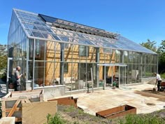 two men are working on the construction of a house with glass walls and roofing