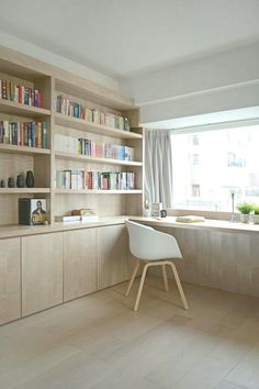 a chair sitting in front of a window next to a book shelf filled with books