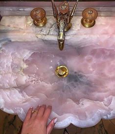 a person's hand is reaching into a sink that has pink marble on it