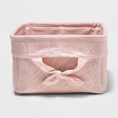 a pink fabric storage box with a bow on the front and bottom, sitting against a white background