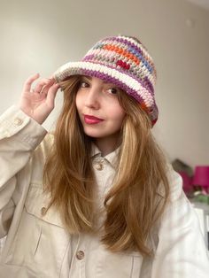 a woman with long hair wearing a multicolored knitted beanie hat, looking at the camera