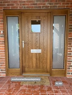 a wooden door with two sidelights and glass panels on the front of a brick building