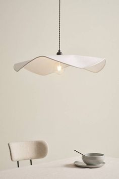 a table with a bowl, plate and lamp hanging from it's ceiling fixture