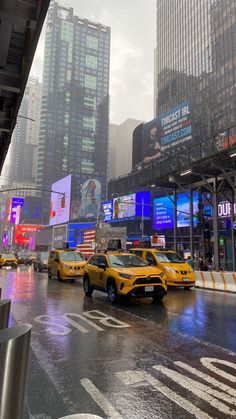 taxi cabs are parked on the street in front of tall buildings and billboards