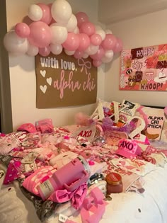 a bed topped with lots of pink and white balloons next to a wall hanging above it