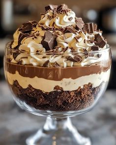 a dessert in a glass bowl with chocolate and cream toppings on top, sitting on a table