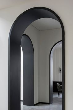 an arch shaped mirror in the middle of a room with white walls and flooring