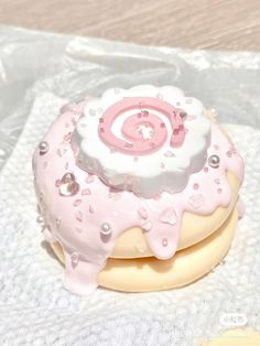 a pink and white cake with icing on it sitting on top of a table