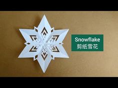 an origami snowflake is displayed on a brown surface with the words snowflake written in chinese